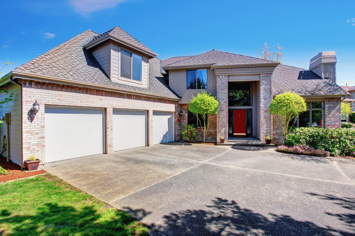 Beautiful large two story home with custom concrete driveway in daytime, greenery
