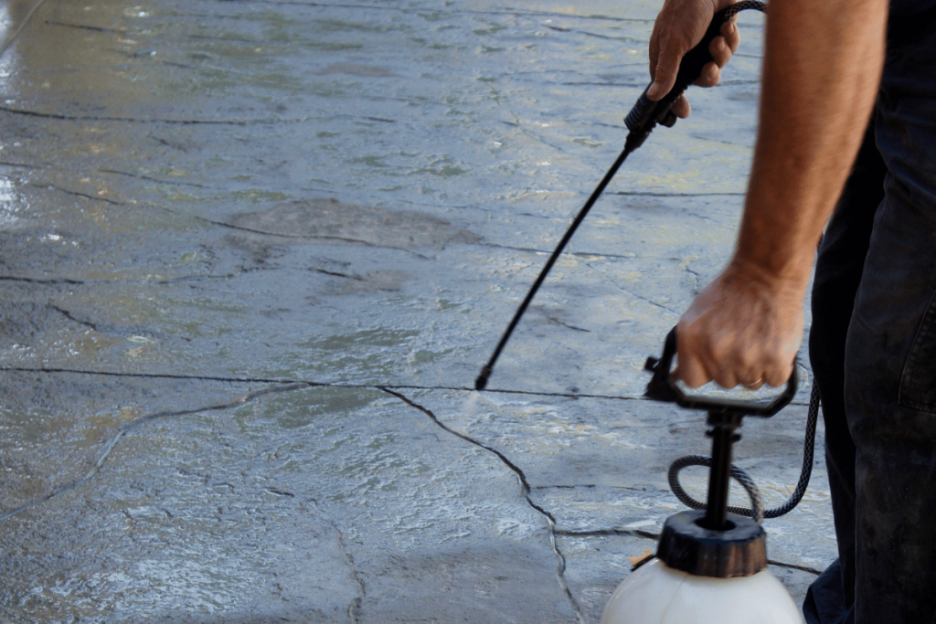 Man applying sealer to grey stamped concrete