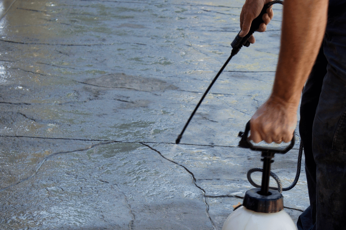 Man applying sealer to grey stamped concrete