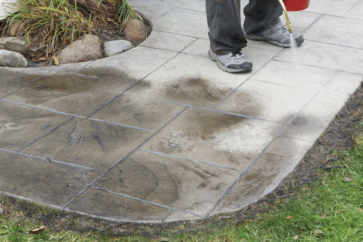 Persona applying sealer to grey stamped concrete.