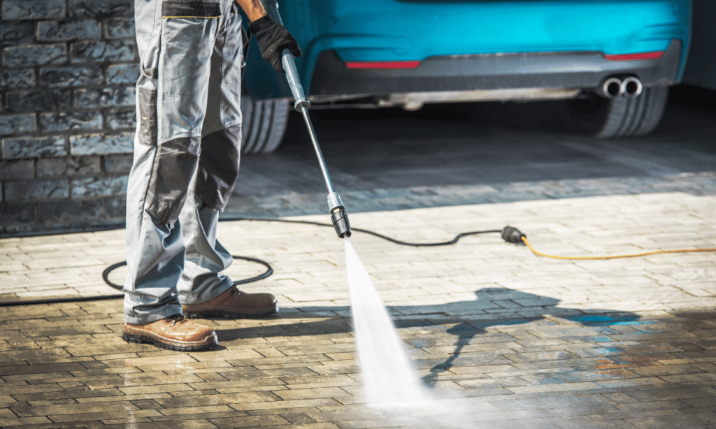 Person pressure washes and cleans concrete driveway