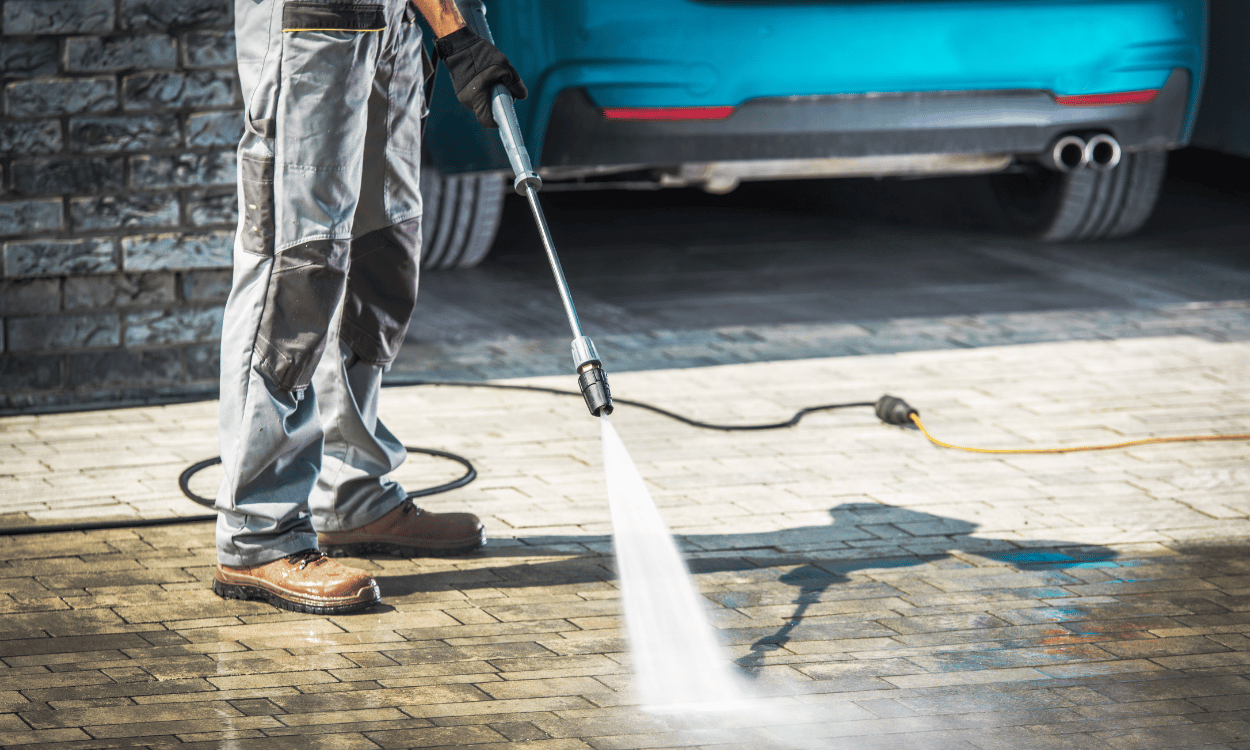 Person pressure washes and cleans concrete driveway